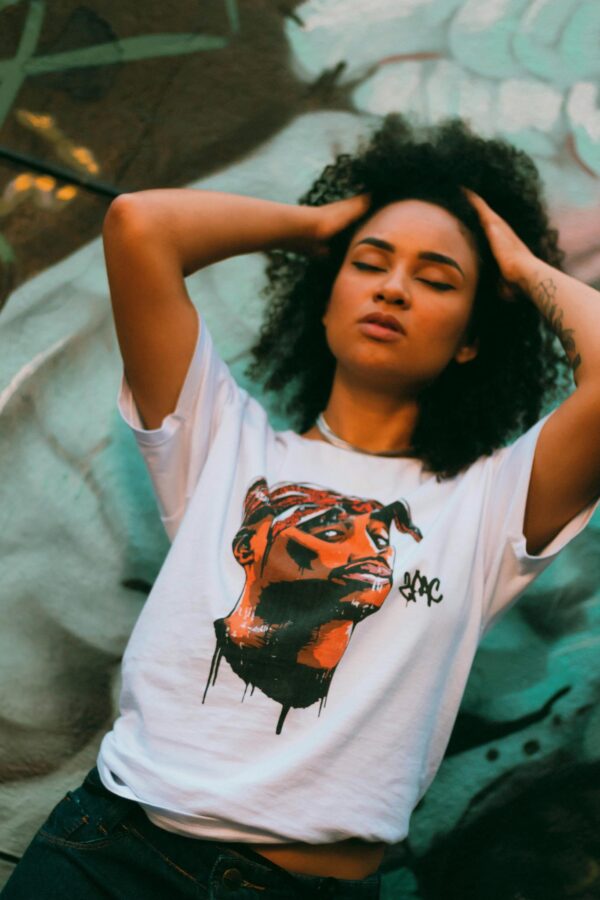 Striking portrait of a woman with curly hair and a graphic t-shirt in vibrant urban setting.