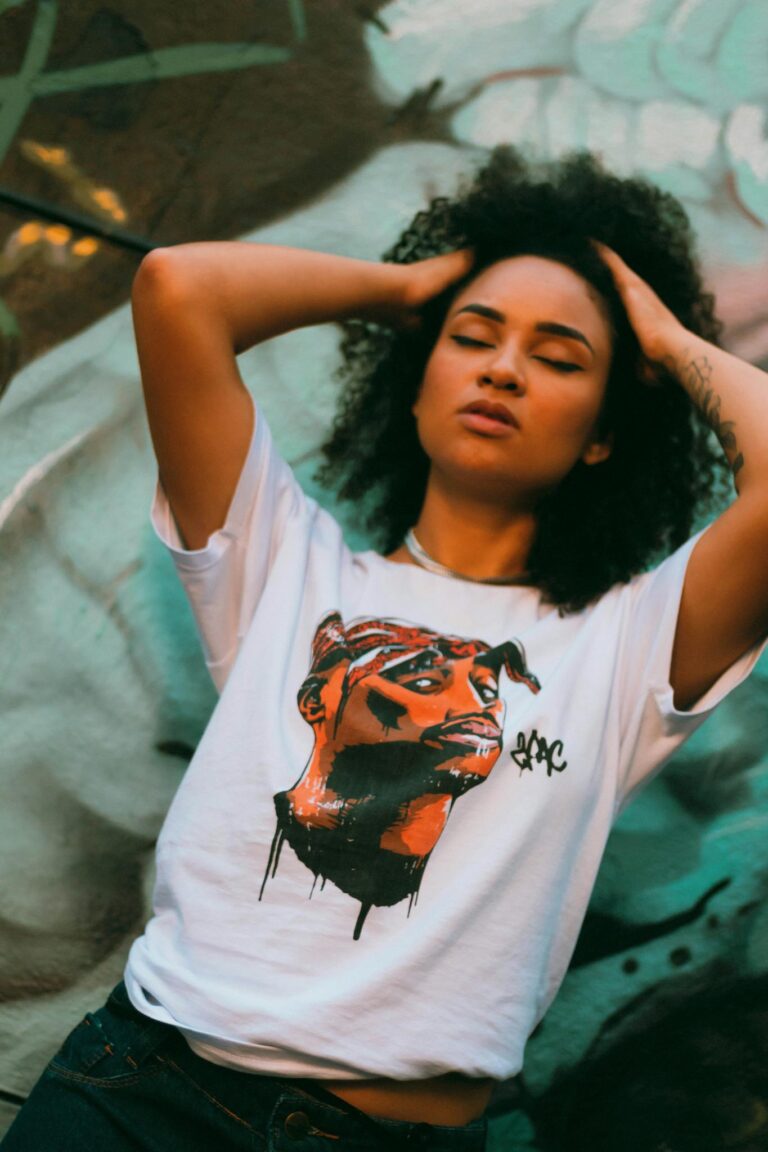 Striking portrait of a woman with curly hair and a graphic t-shirt in vibrant urban setting.