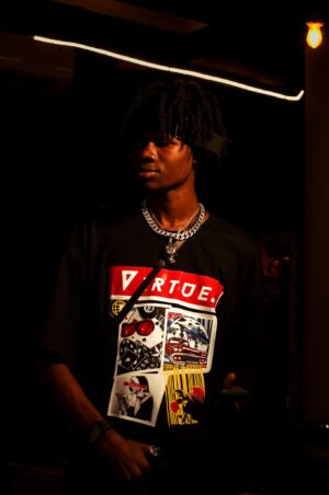 Stylish young man in graphic tee, illuminated against a dark background.